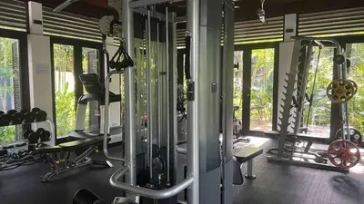 a gym with several treadmills and machines and windows at Bangtao Beach Gardens 2 bedroom villa near Surin beach in Ban Lum Fuang