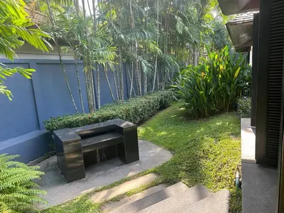 a black bench sitting in the middle of a garden at Bangtao Beach Gardens 2 bedroom villa near Surin beach in Ban Lum Fuang