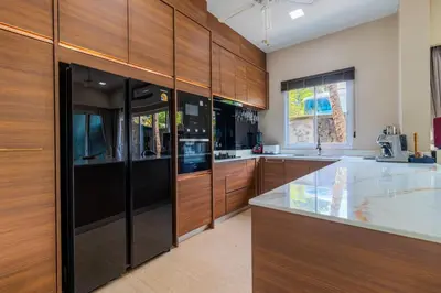 a kitchen with wooden cabinets and a counter top at 10 bed,12 bath, 3 pools,zip-line,sauna, Ocean view in Ban Saiyuan (1)