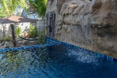 a swimming pool with a waterfall and an umbrella at 10 bed,12 bath, 3 pools,zip-line,sauna, Ocean view in Ban Saiyuan (1)