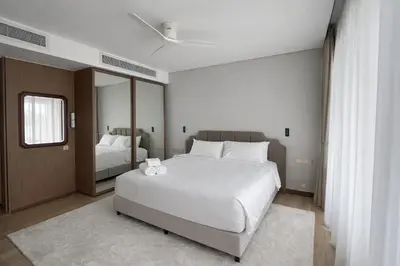 a bedroom with a large white bed and a mirror at Апартаменты в Angsana, Банг Тао in Laguna Phuket