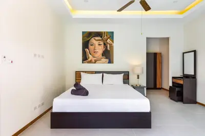 a bedroom with a bed and a painting on the wall at Tropical 4 BR Pool Villa Mika in Rawai Beach