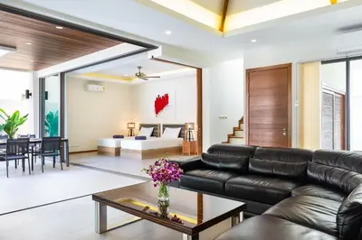 a living room with a black leather couch and a table at Tropical 4 BR Pool Villa Mika in Rawai Beach