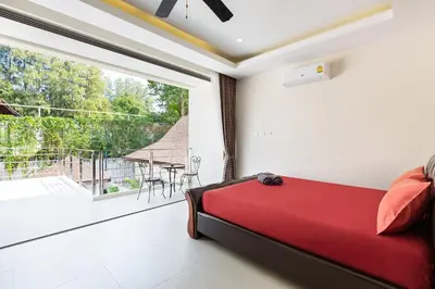 a bedroom with a red bed and a large window at Tropical 4 BR Pool Villa Mika in Rawai Beach