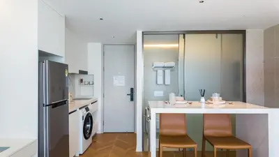 a kitchen with a counter with chairs and a refrigerator at Studio 50 meter from Layan Beach in Layan Beach