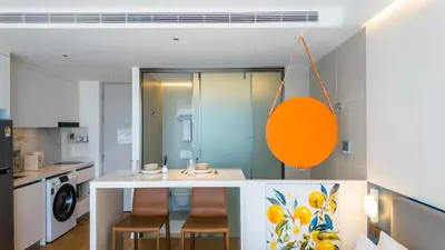 a kitchen with a counter with chairs and a sink at Studio 50 meter from Layan Beach in Layan Beach