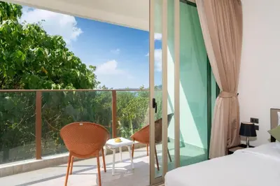 a bedroom with a balcony with a bed and two chairs at Seaview 1BR Apt Oceana C36 near Kamala Beach in Kamala Beach