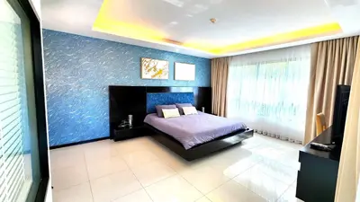 a bedroom with a bed and a blue wall at Phuket Apartment Kamala Regent Condo in Kamala Beach
