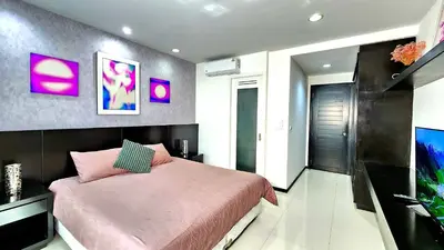 a bedroom with a pink bed and a flat screen tv at Phuket Apartment Kamala Regent Condo in Kamala Beach