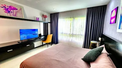 a bedroom with a bed and a desk and a television at Phuket Apartment Kamala Regent Condo in Kamala Beach