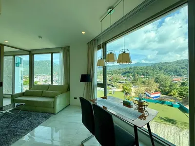 a living room with a table and a large window at 1BR Panoramic Mountain View Walk to Beach by Renttini in Kamala Beach