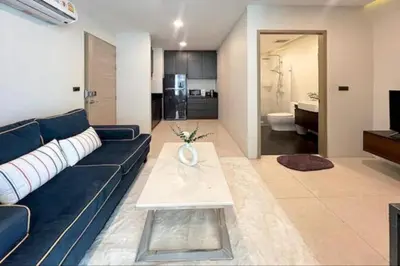 a living room with a blue couch and a kitchen at Beach and Party in Patong with 1BR Apt - Viva B402 in Patong Beach