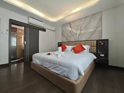 a bedroom with a large white bed with red pillows at JJame Pool Villa Patong in Patong Beach