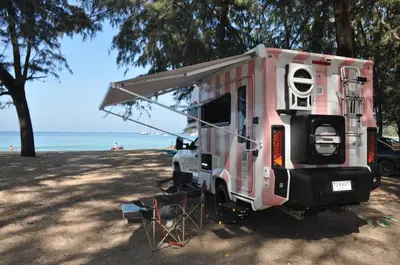 a pink camper parked next to the beach at CoconutRoads Self Drive Motorhome in Phuket