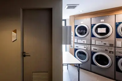 a laundry room with four washing machines and a door at Premium apartment in Laguna in Thalang
