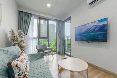 a living room with a couch and a tv on a wall at Premium apartment in Laguna in Thalang