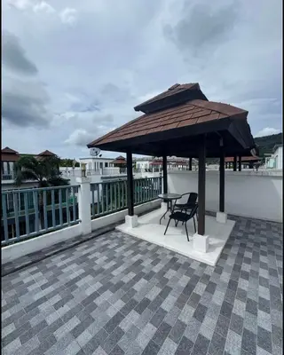 a table and chair under a large umbrella on a roof at Kamala Cozy Townhouse in Kamala Beach