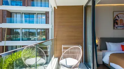 a balcony with two wicker chairs and a bed at Apartment 50 metres from the sea on Bangtao beach in Layan Beach