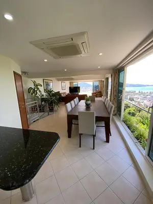 a dining room with a table and chairs and a living room at Andaman hill pool Seaview three bedroom in Patong Beach