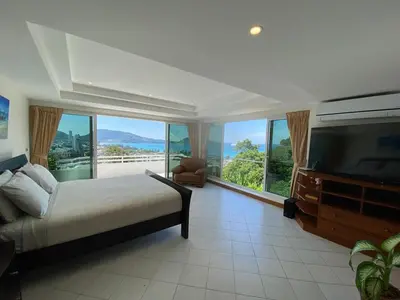 a bedroom with a bed and a tv and large windows at Andaman hill pool Seaview three bedroom in Patong Beach