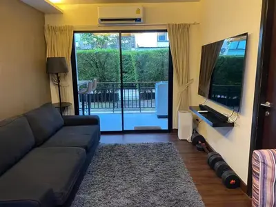 a living room with a black couch and a television at Beach Front Condo on Rawai Beach in Rawai Beach