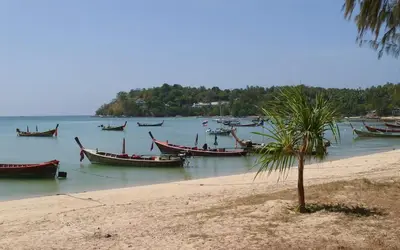 a group of boats in the water on a beach at Beach Front Condo on Rawai Beach in Rawai Beach