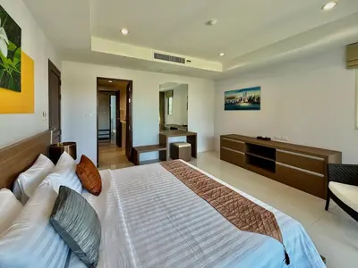 a bedroom with a large bed and a desk at Bangtao Tropical Residence by Villacarte in Ban Lum Fuang