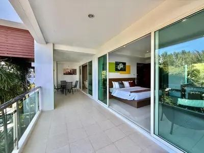 a room with a bed and a balcony with a bedroom at Bangtao Tropical Residence by Villacarte in Ban Lum Fuang