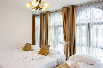 two beds in a room with a large window at Baan Sino Phuket in Ban Phlu Yai