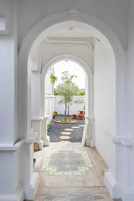 an archway leading to a courtyard with a tree at Baan Sino Phuket in Ban Phlu Yai