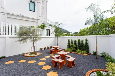 a patio with picnic tables and benches in front of a building at Baan Sino Phuket in Ban Phlu Yai