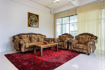 a living room with two couches and a table on a red rug at Baan Sino Phuket in Ban Phlu Yai