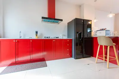 a kitchen with red cabinets and a black refrigerator at Baan Sino Phuket in Ban Phlu Yai