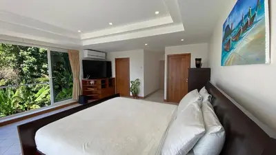 a bedroom with a large bed and a large window at Andaman Hills pool Seaview house in Patong Beach