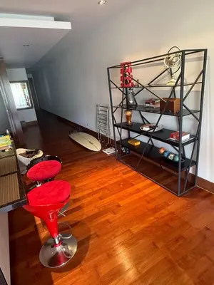 a living room with a red chair and a wooden floor at Beachfront 2BR Apartment with Pool View in Nai Thon Beach