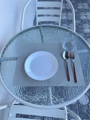 a glass table with a plate and silverware on it at Guest Room Bang Tao MMA in Ban Thalat Choeng Thale