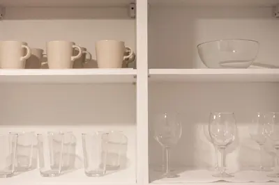two shelves with wine glasses and cups on them at The Ozone Bangtao by Beringela in Laguna Phuket