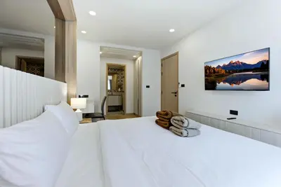 a white bedroom with a large white bed and a desk at The Ozone Bangtao by Beringela in Laguna Phuket