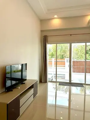 a living room with a television and a sliding glass door at Cozy Thai-Style House with Private Pool, Bang Tao in Ban Pak Lak