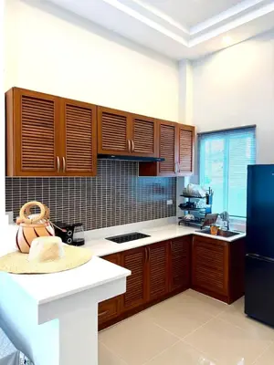 a kitchen with wooden cabinets and a black refrigerator at Cozy Thai-Style House with Private Pool, Bang Tao in Ban Pak Lak