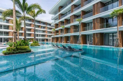a swimming pool with chairs in front of a building at Studio Apartment by Sunshine Beach in Layan Beach