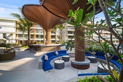 an outdoor patio with blue seating and trees at Studio Apartment by Sunshine Beach in Layan Beach