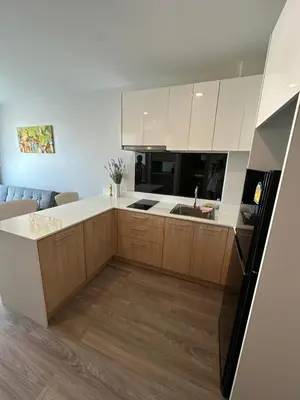 a kitchen with white cabinets and a black refrigerator at 2 комнатные апартаменты с одной спальней и кухней-гостиной in Phuket Town