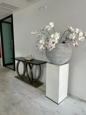 a vase of flowers on a stand next to a table at 2 комнатные апартаменты с одной спальней и кухней-гостиной in Phuket Town