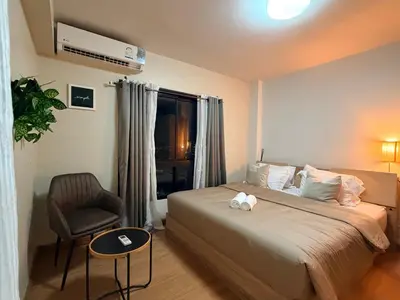 a bedroom with a bed and a chair and a window at 1BR Apartment Suite in the heart of Phuket Town in Ban Lo Long