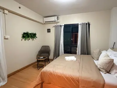 a bedroom with a bed and a chair and a window at 1BR Apartment Suite in the heart of Phuket Town in Ban Lo Long