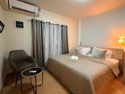 a bedroom with a bed and a chair and a window at 1BR Apartment Suite in the heart of Phuket Town in Ban Lo Long