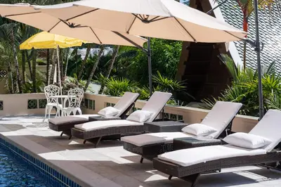 a group of chairs and umbrellas next to a pool at D Villa Phuket-Luxury 6-Bedroom Private Villa in Panwa Entire Place in Phuket Town