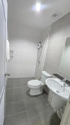 a white bathroom with a toilet and a sink at Joyful House Naiyang beach in Thalang
