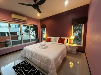 a bedroom with a large bed with a ceiling fan at Kamala cozy home in Kamala Beach